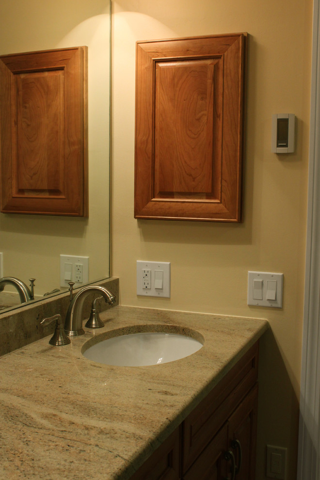 Exempel på ett mellanstort klassiskt en-suite badrum, med ett undermonterad handfat, luckor med upphöjd panel, skåp i mellenmörkt trä, granitbänkskiva, en dubbeldusch, en toalettstol med hel cisternkåpa, brun kakel, porslinskakel, beige väggar och klinkergolv i porslin