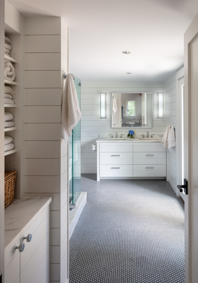 Example of a mid-sized farmhouse master mosaic tile floor and gray floor corner shower design in Providence with white cabinets, a one-piece toilet, white walls, an undermount sink, marble countertops, a hinged shower door and white countertops