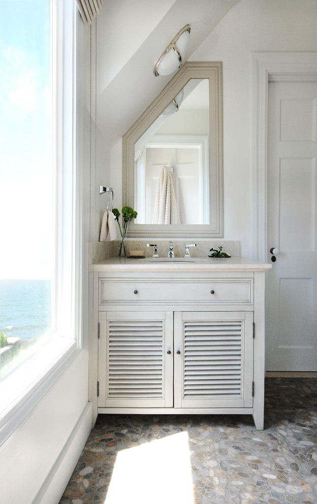 Maritim inredning av ett mellanstort badrum med dusch, med ett undermonterad handfat, luckor med lamellpanel, vita skåp, marmorbänkskiva, vita väggar och klinkergolv i småsten