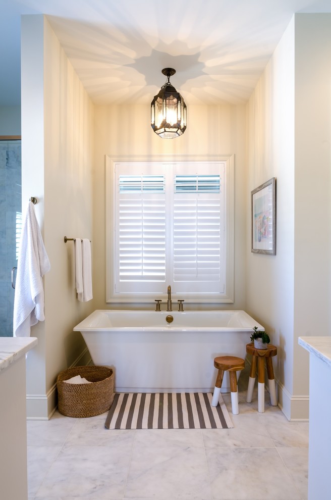 Foto de cuarto de baño principal clásico renovado con puertas de armario blancas, bañera exenta, paredes blancas, suelo de mármol, encimera de mármol y suelo gris