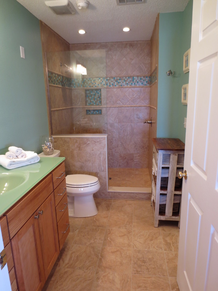Foto på ett litet maritimt en-suite badrum, med ett integrerad handfat, skåp i shakerstil, skåp i mellenmörkt trä, bänkskiva i glas, en öppen dusch, en toalettstol med separat cisternkåpa, blå kakel, blå väggar och klinkergolv i porslin