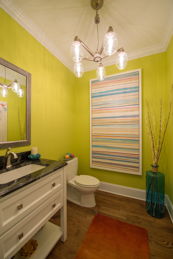 Réalisation d'une salle de bain tradition de taille moyenne avec un placard avec porte à panneau encastré, des portes de placard blanches, un mur vert, un sol en bois brun et un lavabo encastré.