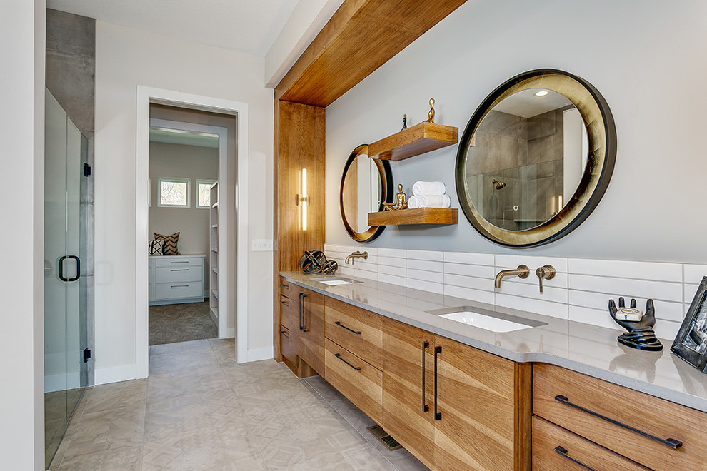 Aménagement d'une salle de bain principale bord de mer en bois clair avec un carrelage blanc, une cabine de douche à porte battante, un plan de toilette gris, meuble double vasque et meuble-lavabo encastré.
