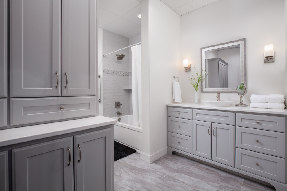 Inredning av ett klassiskt vit vitt badrum, med släta luckor, grå skåp, ett platsbyggt badkar, en dusch/badkar-kombination, vita väggar, vinylgolv, ett fristående handfat, bänkskiva i kvarts, grått golv och dusch med duschdraperi