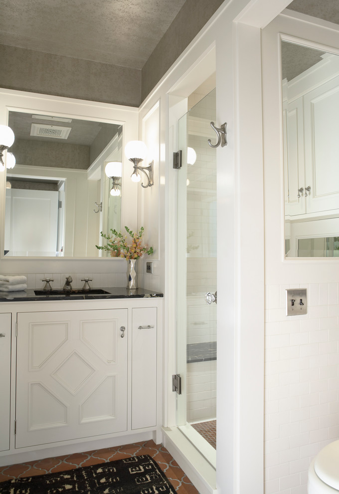 Пример оригинального дизайна: ванная комната в стиле неоклассика (современная классика) с белыми фасадами, душем в нише, белой плиткой, плиткой кабанчик, белыми стенами, полом из терракотовой плитки, врезной раковиной и душевой кабиной