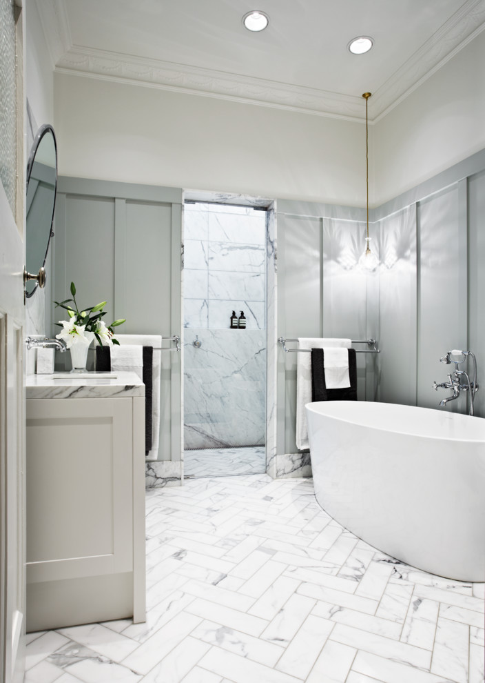 Inredning av ett klassiskt badrum, med ett fristående badkar, grå väggar och marmorkakel