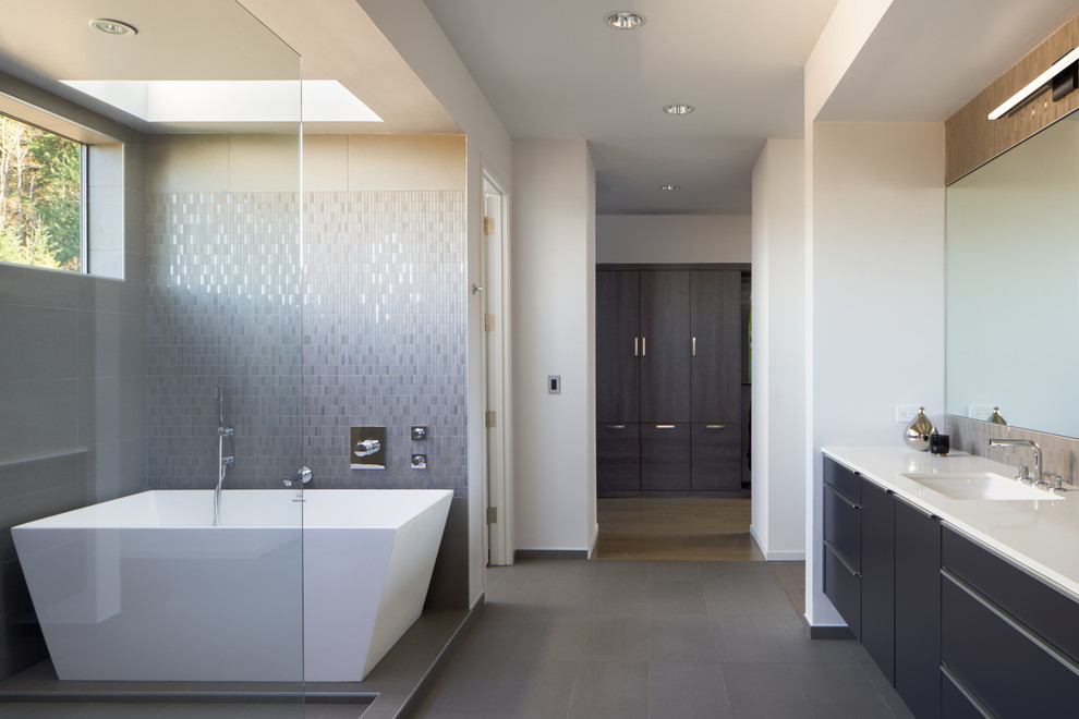 Example of a large trendy master gray tile and ceramic tile ceramic tile bathroom design in Seattle with flat-panel cabinets, dark wood cabinets, a two-piece toilet, white walls, an undermount sink and quartz countertops