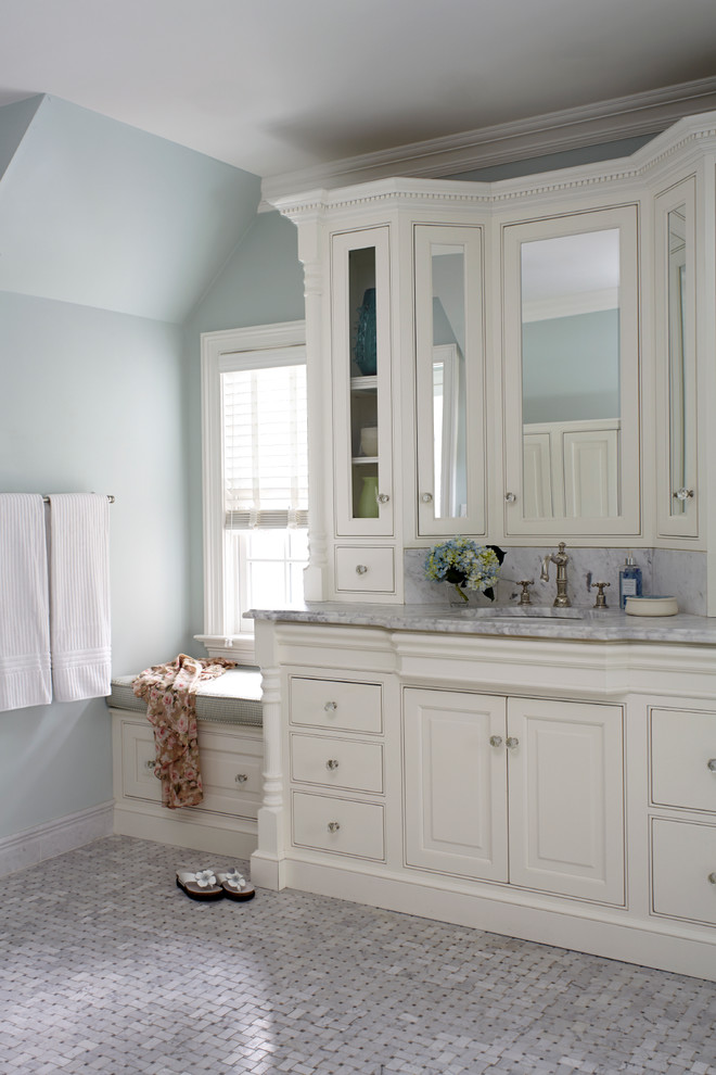 Modelo de cuarto de baño tradicional con paredes azules, armarios con paneles con relieve, puertas de armario blancas y suelo con mosaicos de baldosas