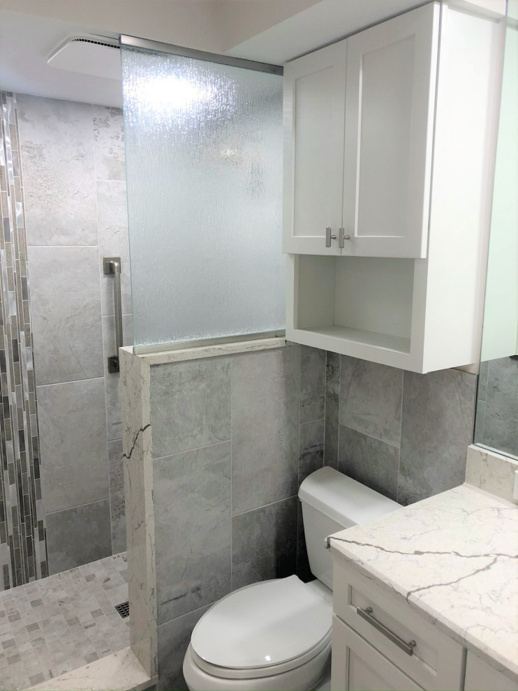 Cette photo montre une petite salle de bain principale moderne avec un placard à porte shaker, des portes de placard blanches, une douche ouverte, WC à poser, un carrelage gris, des carreaux de porcelaine, un mur gris, un sol en carrelage de porcelaine, un lavabo encastré, un plan de toilette en quartz, un sol gris, aucune cabine, un plan de toilette blanc, une niche, meuble simple vasque et meuble-lavabo encastré.