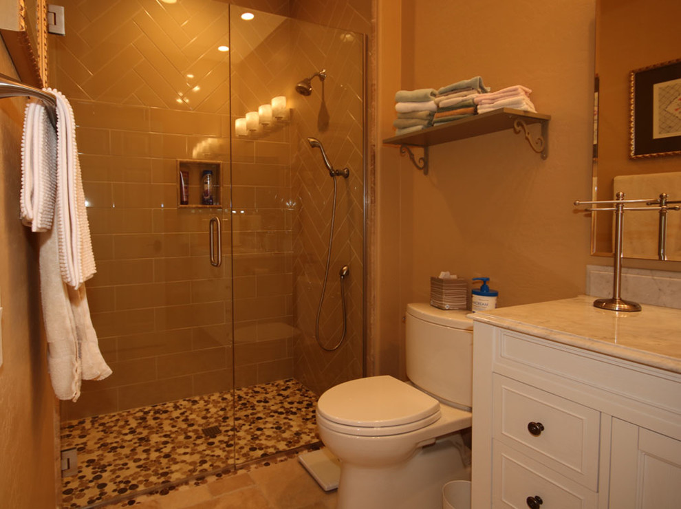 Inspiration för ett litet vintage vit vitt badrum med dusch, med möbel-liknande, vita skåp, en dubbeldusch, en toalettstol med separat cisternkåpa, beige kakel, porslinskakel, beige väggar, travertin golv, ett väggmonterat handfat, marmorbänkskiva, beiget golv och dusch med gångjärnsdörr