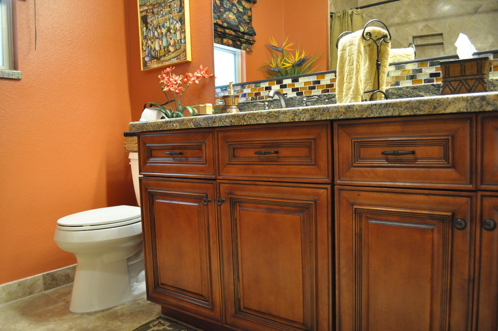 Bild på ett mellanstort rustikt badrum med dusch, med ett undermonterad handfat, luckor med upphöjd panel, skåp i mellenmörkt trä, granitbänkskiva, en dusch i en alkov, en toalettstol med hel cisternkåpa, beige kakel, glasskiva, orange väggar och klinkergolv i keramik