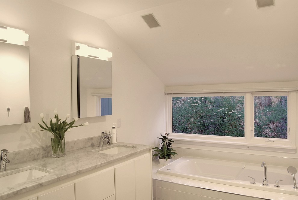 Bild på ett mellanstort funkis en-suite badrum, med ett undermonterad handfat, släta luckor, vita skåp, marmorbänkskiva, ett platsbyggt badkar, vit kakel, porslinskakel och vita väggar
