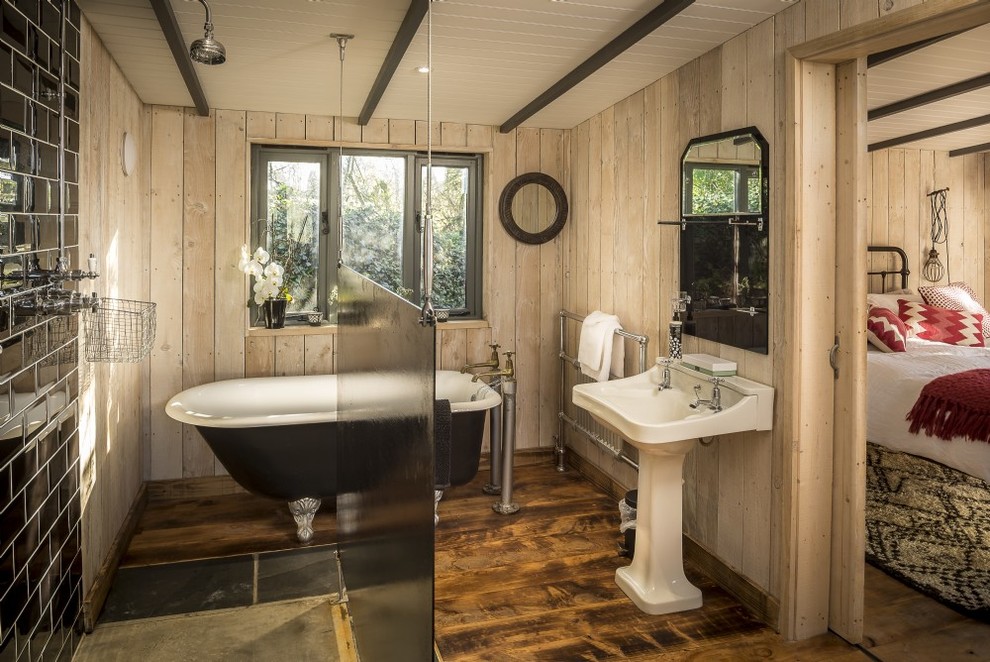 Cette image montre une salle de bain principale chalet en bois brun de taille moyenne avec un placard à porte shaker, une baignoire sur pieds, une douche ouverte, WC séparés, un carrelage beige, des carreaux de céramique, un mur beige, un sol en bois brun, un lavabo de ferme, un sol beige et aucune cabine.