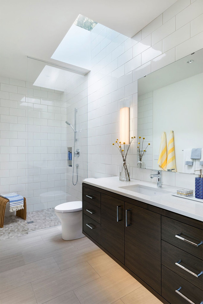 Réalisation d'une salle de bain design en bois foncé avec un placard à porte plane, un carrelage blanc, un lavabo encastré, un sol gris et un plan de toilette blanc.