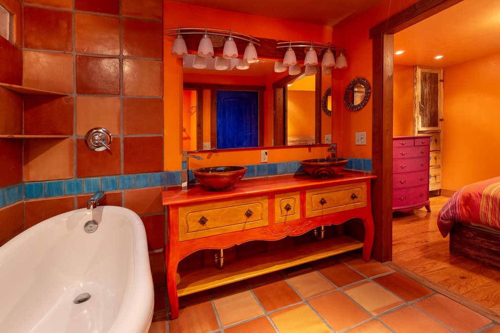 Inspiration for an ensuite bathroom in Other with freestanding cabinets, orange cabinets, a claw-foot bath, a walk-in shower, a one-piece toilet, orange tiles, terracotta tiles, orange walls, terracotta flooring, a vessel sink, orange floors, a shower curtain and orange worktops.