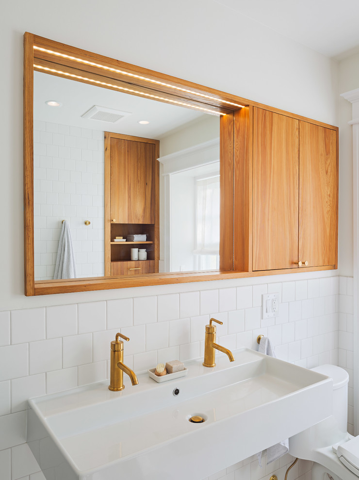Example of a mid-sized minimalist master white tile and porcelain tile porcelain tile and white floor bathroom design in Philadelphia with flat-panel cabinets, medium tone wood cabinets, a one-piece toilet, white walls, a trough sink, quartz countertops and white countertops
