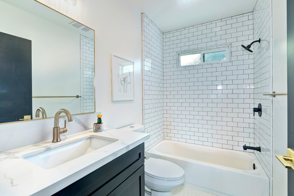 Classic shower room bathroom in Los Angeles with shaker cabinets, black cabinets, an alcove bath, a shower/bath combination, a two-piece toilet, white tiles, metro tiles, white walls, a submerged sink, white floors and white worktops.