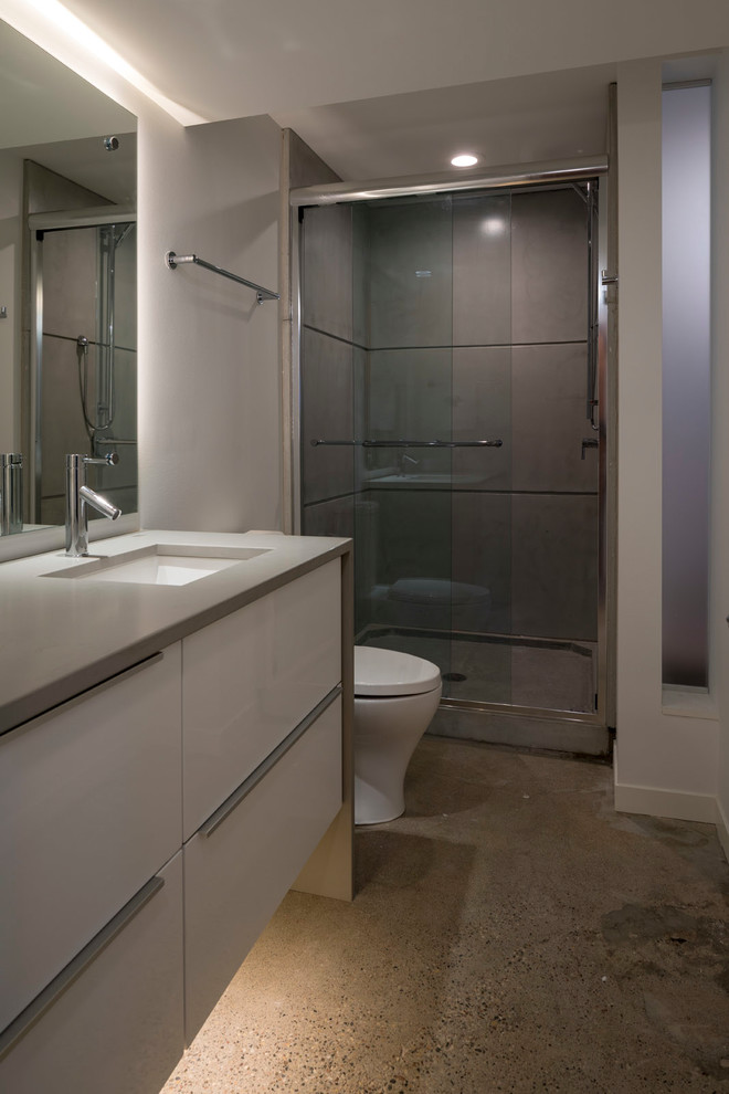 Idéer för ett mellanstort modernt grå en-suite badrum, med släta luckor, vita skåp, ett fristående badkar, en dusch i en alkov, en toalettstol med hel cisternkåpa, grå kakel, cementkakel, vita väggar, klinkergolv i keramik, ett undermonterad handfat, bänkskiva i kvarts, grått golv och dusch med skjutdörr