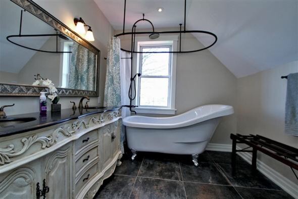 Immagine di una stanza da bagno country con lavabo sottopiano, top in pietra calcarea, vasca con piedi a zampa di leone, vasca/doccia, WC monopezzo e pareti beige
