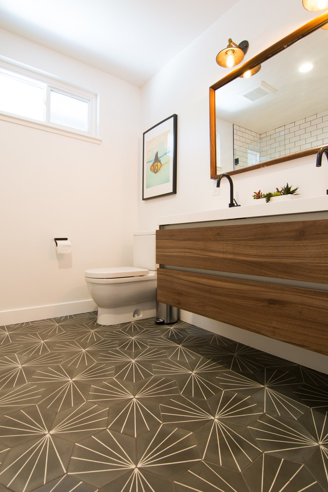 This is an example of a medium sized eclectic family bathroom in San Francisco with flat-panel cabinets, medium wood cabinets, a built-in bath, a one-piece toilet, white tiles, porcelain tiles, white walls, cement flooring, a built-in sink, solid surface worktops, grey floors and white worktops.