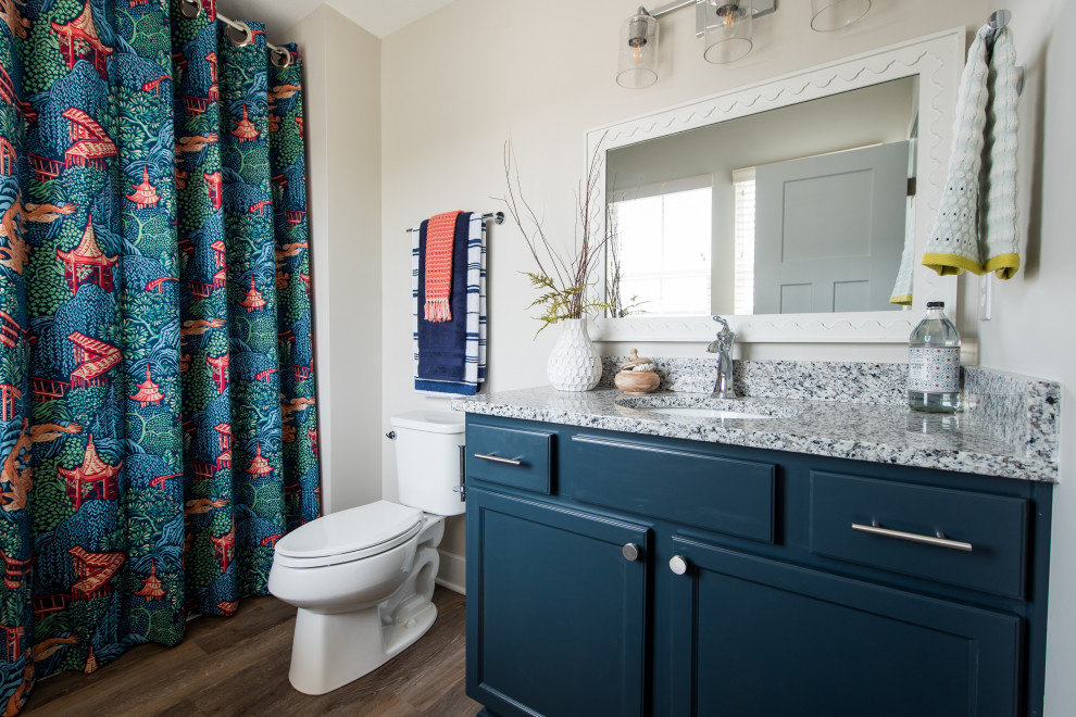 Inspiration för ett mellanstort funkis grå grått badrum med dusch, med luckor med upphöjd panel, blå skåp, våtrum, en toalettstol med hel cisternkåpa, mörkt trägolv, ett undermonterad handfat, granitbänkskiva och dusch med duschdraperi