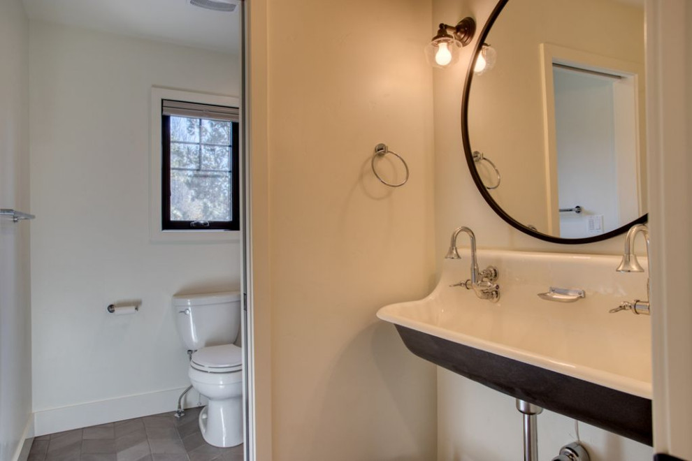 Photo of a country bathroom in Salt Lake City with black cabinets, an alcove bath, a shower/bath combination, a two-piece toilet, white tiles, metro tiles, white walls, a trough sink, beige floors and a shower curtain.
