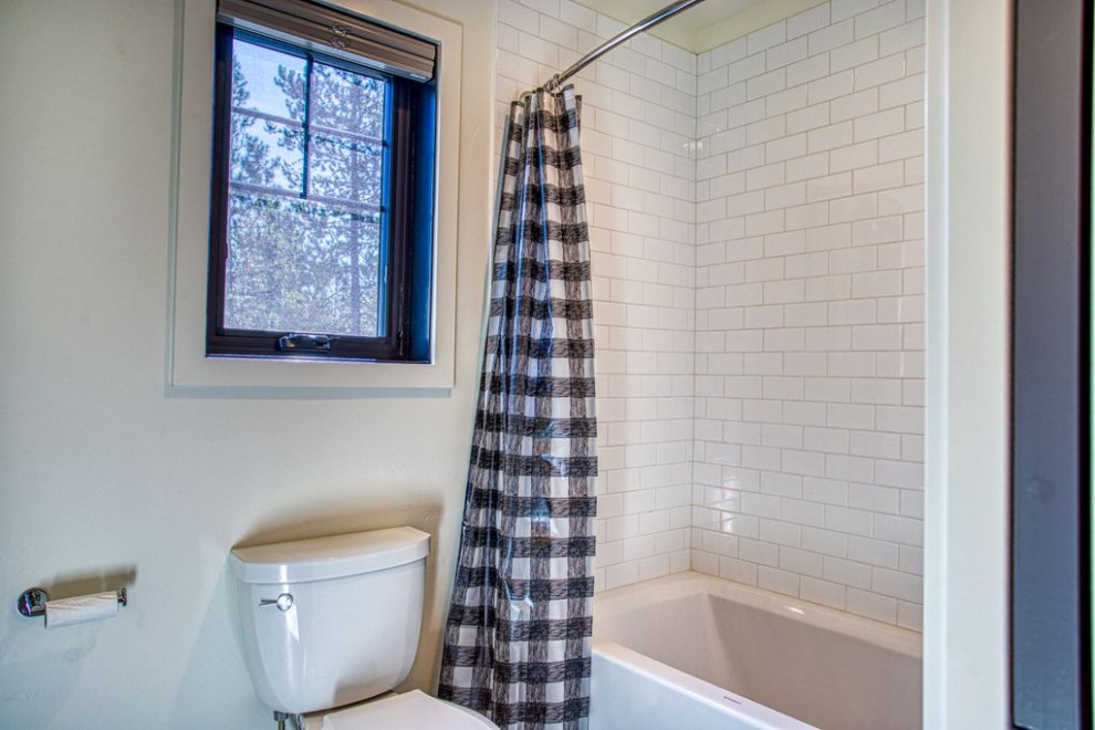 Foto på ett lantligt badrum, med ett badkar i en alkov, en dusch/badkar-kombination, en toalettstol med separat cisternkåpa, vit kakel, tunnelbanekakel, vita väggar, beiget golv och dusch med duschdraperi