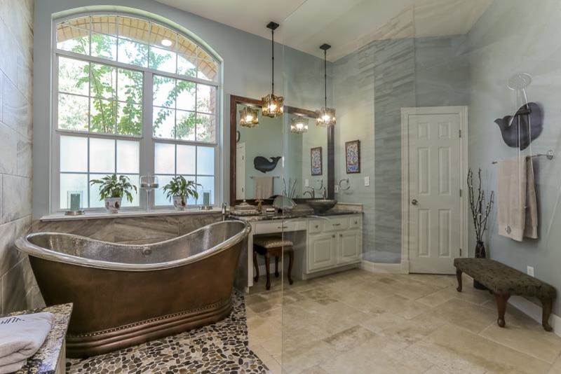 Maritim inredning av ett en-suite badrum, med ett fristående handfat, vita skåp, granitbänkskiva, ett fristående badkar, en kantlös dusch, beige kakel, blå väggar, travertin golv och luckor med upphöjd panel