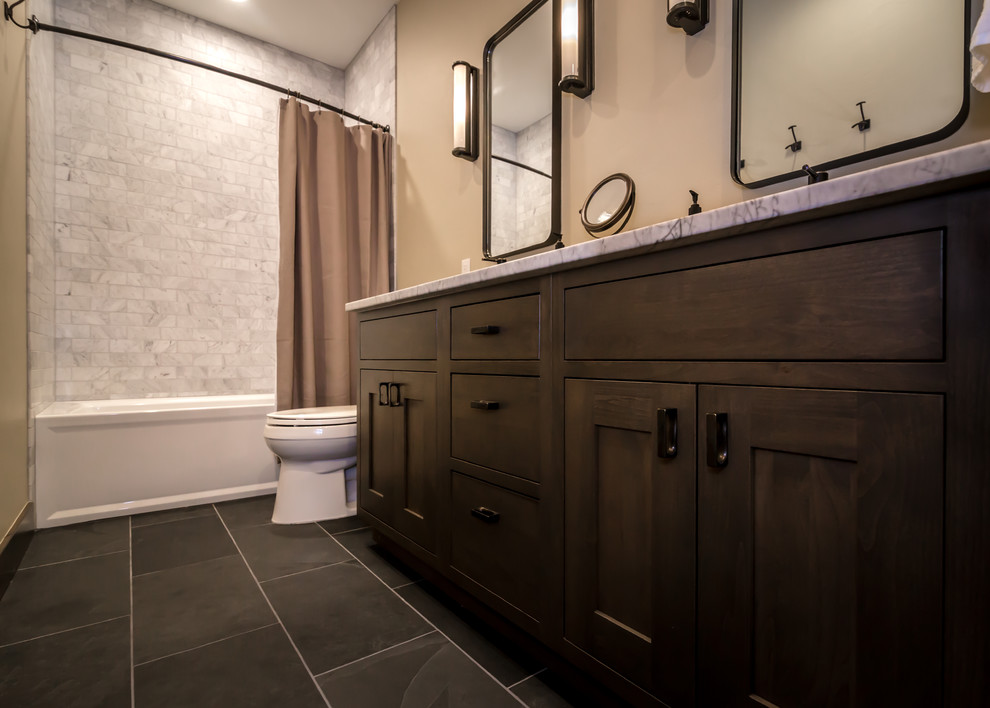 Cette image montre une salle de bain principale chalet en bois foncé de taille moyenne avec un placard à porte shaker, une baignoire en alcôve, un combiné douche/baignoire, WC à poser, un carrelage gris, du carrelage en marbre, un mur beige, un sol en ardoise, un lavabo encastré, un plan de toilette en marbre, un sol gris, une cabine de douche avec un rideau et un plan de toilette gris.