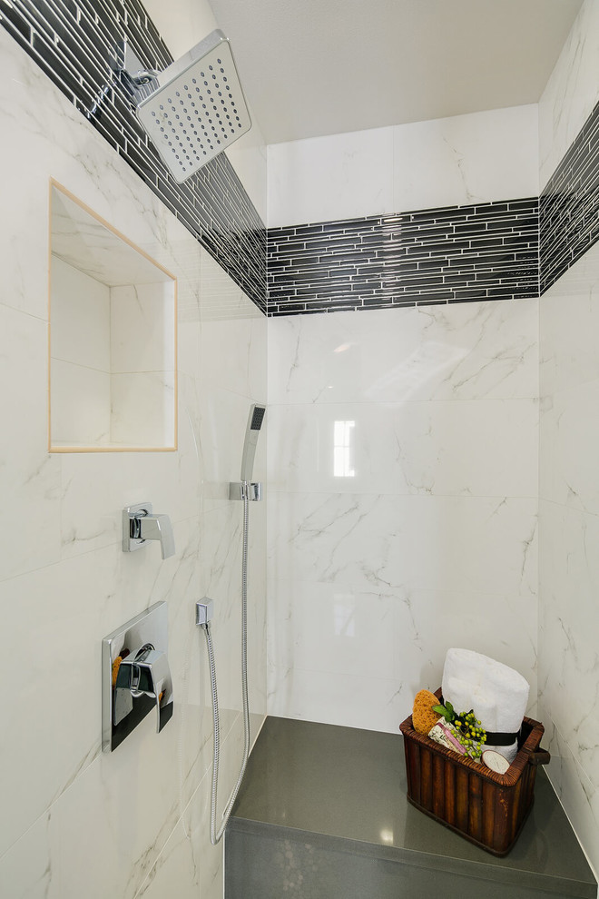Aménagement d'une salle de bain avec des portes de placard noires, une baignoire encastrée, un sol gris et un plan de toilette gris.