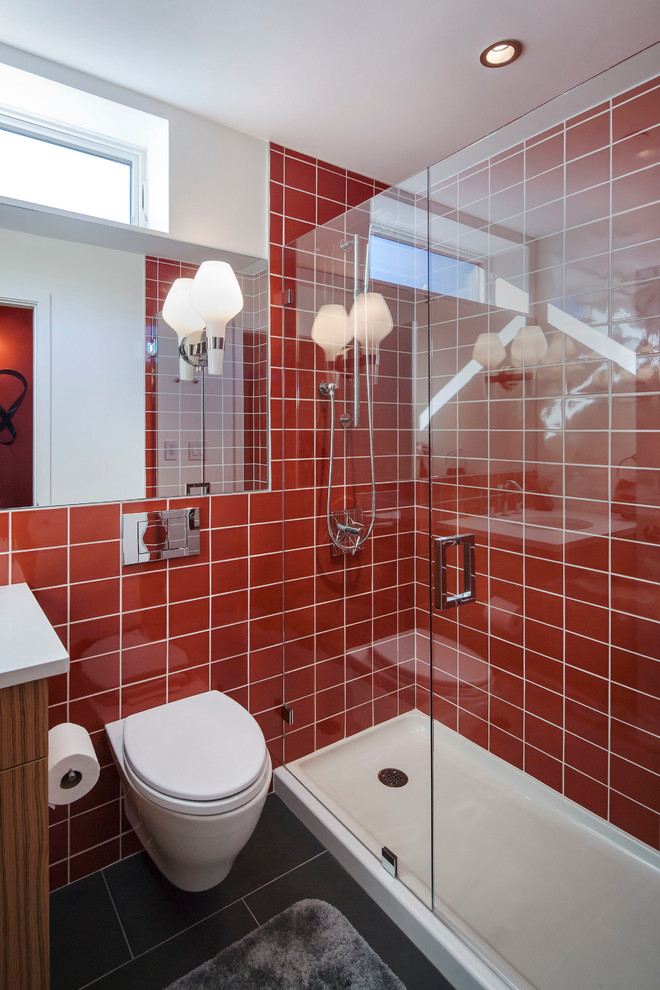 Inredning av ett modernt badrum, med en dusch i en alkov, en vägghängd toalettstol och röd kakel
