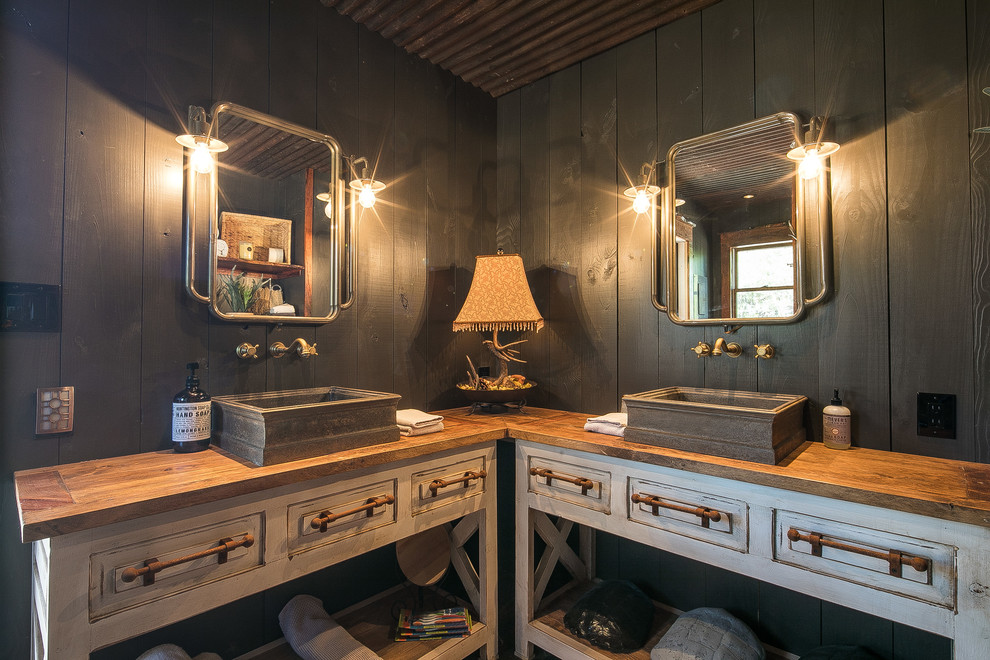 Modelo de cuarto de baño rural con puertas de armario con efecto envejecido, paredes grises, lavabo sobreencimera, encimera de madera, encimeras marrones y armarios con paneles con relieve
