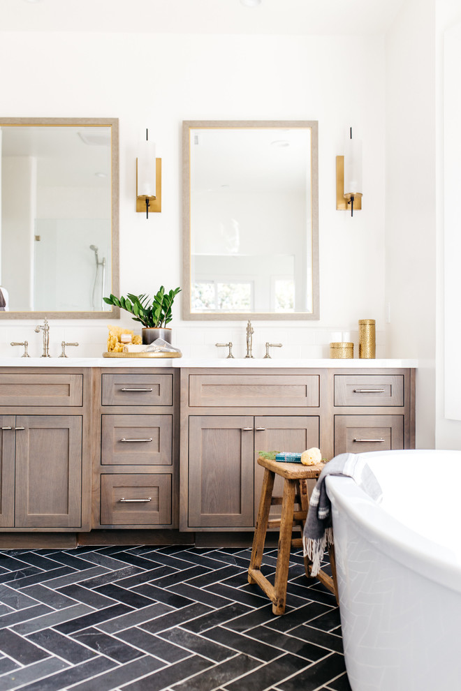 Foto de cuarto de baño clásico renovado con armarios estilo shaker, puertas de armario de madera en tonos medios, bañera exenta y suelo negro