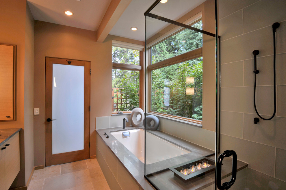 Modelo de cuarto de baño actual con armarios con paneles lisos, puertas de armario de madera clara, bañera encastrada sin remate, ducha esquinera y baldosas y/o azulejos beige