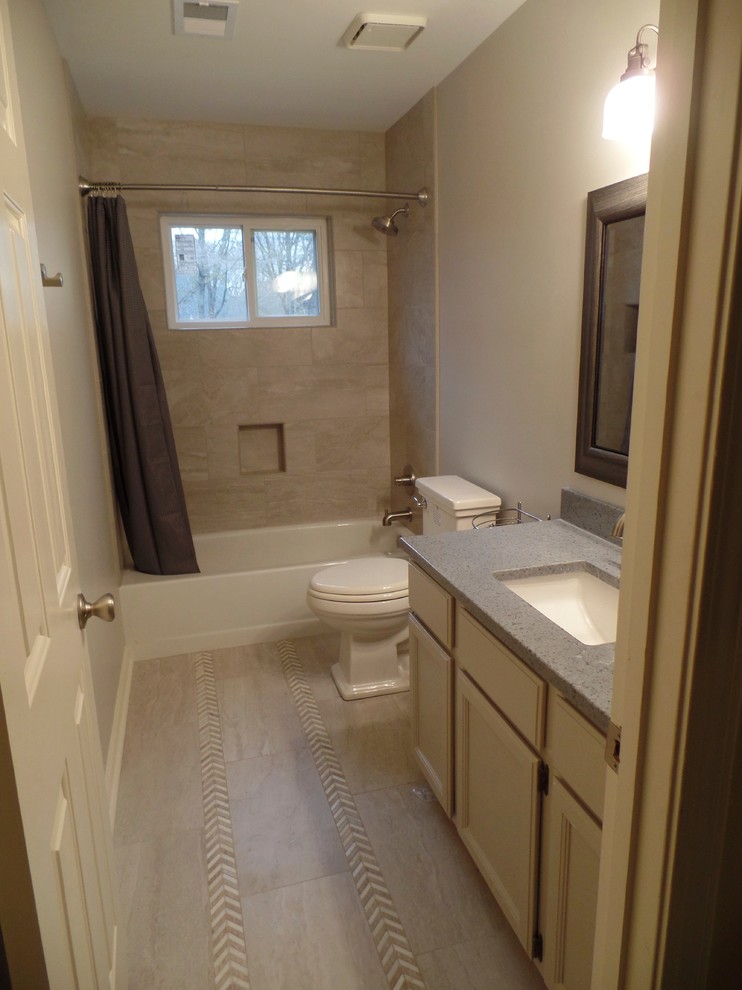 Mid-sized transitional kids' gray tile and porcelain tile porcelain tile bathroom photo in Nashville with an undermount sink, recessed-panel cabinets, gray cabinets, solid surface countertops, a two-piece toilet and gray walls