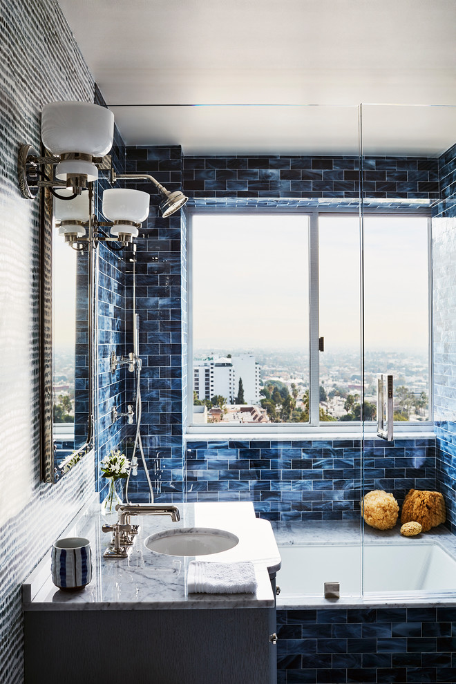 Exemple d'une grande salle de bain principale éclectique avec un placard en trompe-l'oeil, des portes de placard grises, une baignoire en alcôve, un combiné douche/baignoire, un carrelage bleu, un carrelage métro, un mur bleu, un lavabo encastré et une cabine de douche à porte battante.