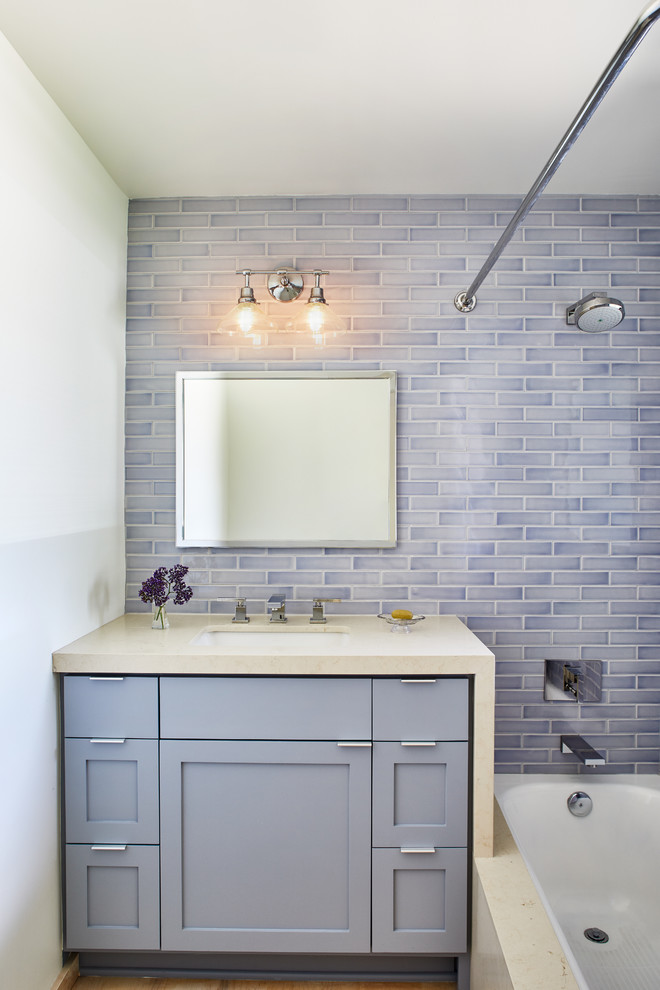 Свежая идея для дизайна: маленькая ванная комната в стиле неоклассика (современная классика) с фасадами в стиле шейкер, синими фасадами, полновстраиваемой ванной, душем над ванной, унитазом-моноблоком, синей плиткой, керамической плиткой, белыми стенами, светлым паркетным полом, врезной раковиной, столешницей из искусственного кварца, бежевым полом, шторкой для ванной и бежевой столешницей для на участке и в саду - отличное фото интерьера