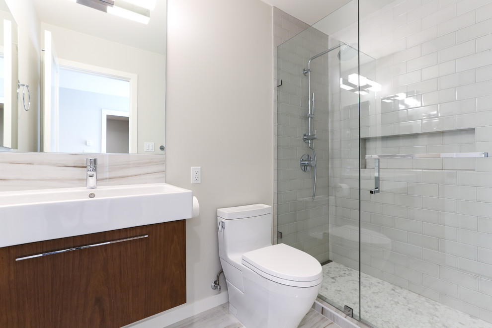 Esempio di una stanza da bagno contemporanea con ante lisce, ante in legno scuro e top in quarzo composito