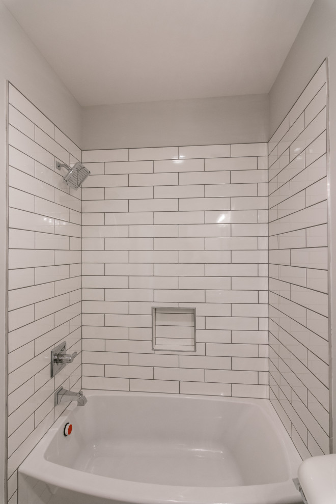 Cette photo montre une salle d'eau nature de taille moyenne avec un placard avec porte à panneau surélevé, des portes de placard blanches, une baignoire en alcôve, un combiné douche/baignoire, WC séparés, un mur gris, un sol en carrelage de porcelaine, un lavabo encastré, un plan de toilette en granite, un sol beige, une cabine de douche avec un rideau et un plan de toilette multicolore.
