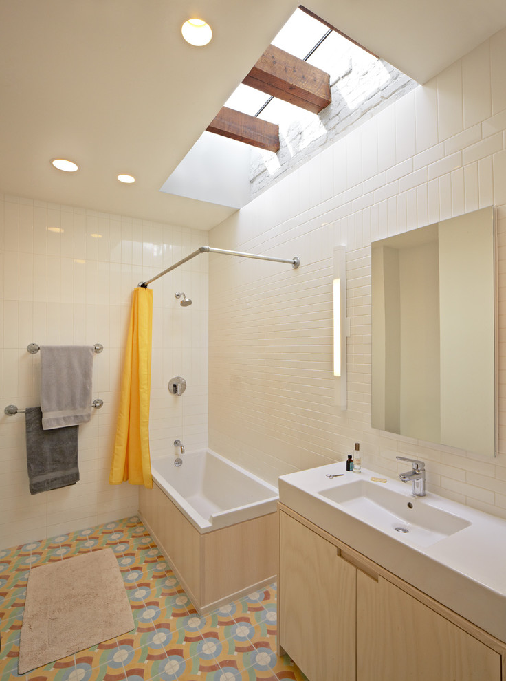Modelo de cuarto de baño infantil contemporáneo con armarios con paneles lisos, puertas de armario de madera clara, bañera encastrada, combinación de ducha y bañera y baldosas y/o azulejos blancos