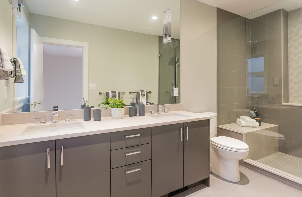 Medium sized contemporary shower room bathroom in Vancouver with flat-panel cabinets, grey cabinets, an alcove shower, a two-piece toilet, grey tiles, porcelain tiles, grey walls, porcelain flooring, a submerged sink, engineered stone worktops, grey floors, a hinged door and white worktops.