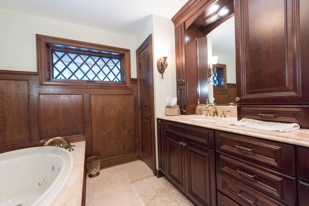 Example of a large classic master ceramic tile drop-in bathtub design in New York with an integrated sink, beaded inset cabinets, dark wood cabinets, granite countertops and white walls