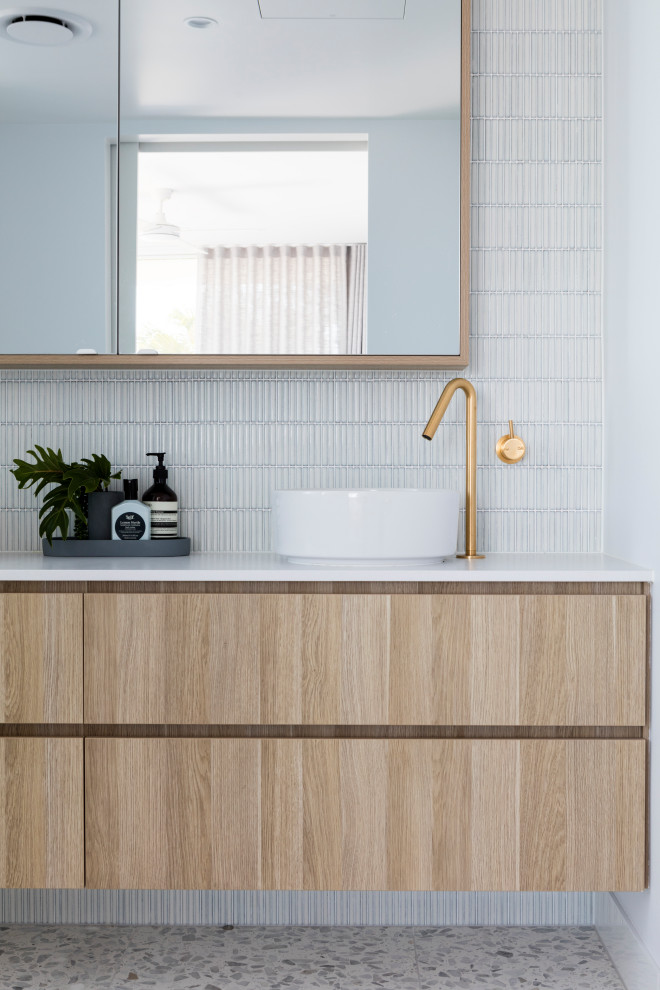 Photo of a nautical bathroom in Sunshine Coast with flat-panel cabinets, light wood cabinets, white tiles, mosaic tiles, white walls, pebble tile flooring, a vessel sink, grey floors, white worktops and a floating vanity unit.