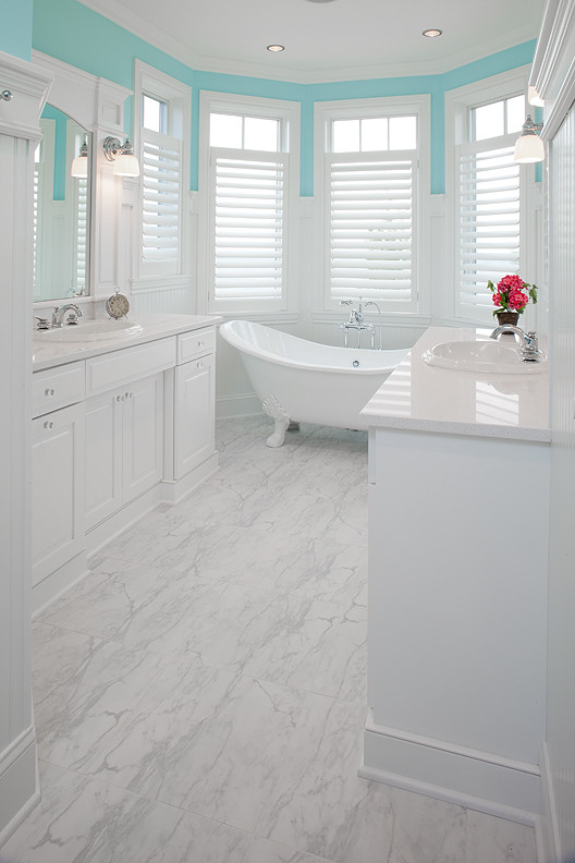 Example of a large classic master marble floor freestanding bathtub design in Grand Rapids with raised-panel cabinets, white cabinets, blue walls, a drop-in sink and solid surface countertops