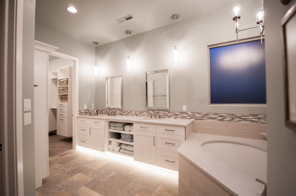 Пример оригинального дизайна: большая главная ванная комната в стиле неоклассика (современная классика) с фасадами в стиле шейкер, белыми фасадами, полновстраиваемой ванной, раздельным унитазом, бежевой плиткой, коричневой плиткой, серой плиткой, керамогранитной плиткой, серыми стенами, полом из керамогранита, врезной раковиной, столешницей из искусственного камня и разноцветным полом