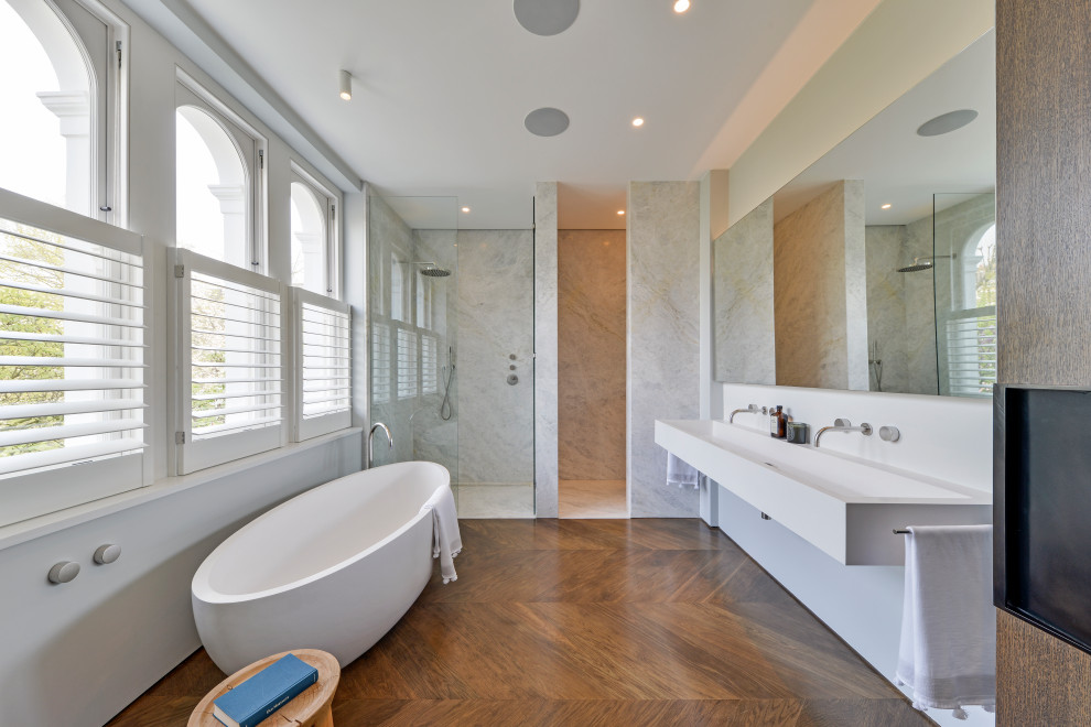 Contemporary ensuite bathroom in London with a freestanding bath, an alcove shower, white walls, a trough sink and brown floors.