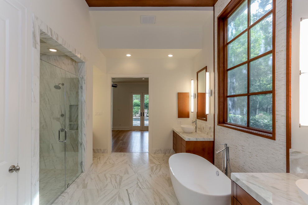 Example of a large trendy master gray tile, white tile and marble tile marble floor and white floor bathroom design in Houston with flat-panel cabinets, medium tone wood cabinets, white walls, a vessel sink, marble countertops and a hinged shower door