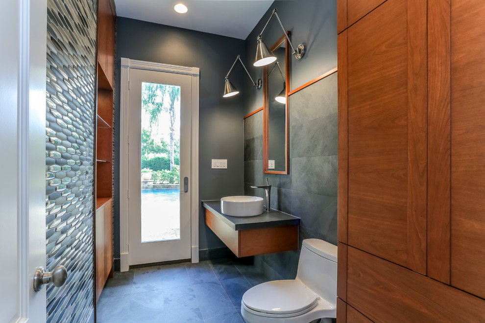 Kleines Modernes Duschbad mit flächenbündigen Schrankfronten, hellbraunen Holzschränken, Toilette mit Aufsatzspülkasten, Aufsatzwaschbecken, grauer Wandfarbe, Schieferboden und schwarzem Boden in Houston