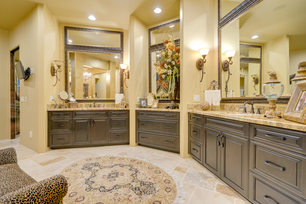 Immagine di una stanza da bagno padronale stile americano con ante con bugna sagomata, ante marroni, pavimento in travertino, lavabo sottopiano e top in granito