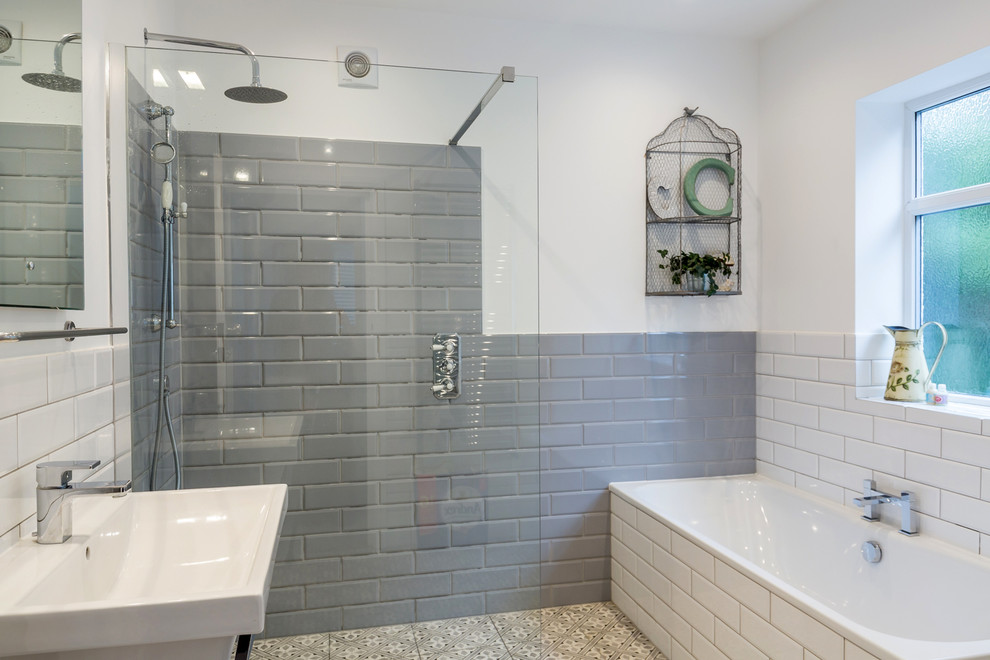 Пример оригинального дизайна: ванная комната среднего размера в стиле неоклассика (современная классика) с угловой ванной, душевой комнатой, серой плиткой, белой плиткой, плиткой кабанчик, белыми стенами, разноцветным полом и открытым душем